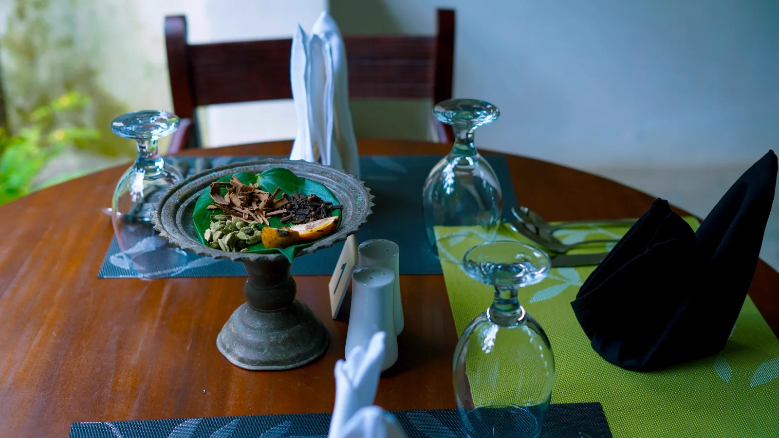 Table setting with a pedestal dish of cinnamon, cloves and cardamom on a betel leaf